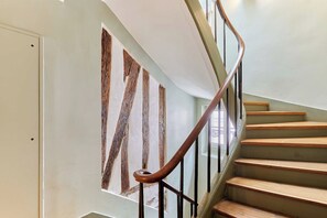 A staircase with wooden steps and a metal handrail, leading to a room with a white door and a large wooden-framed window. - Lovely apartement  with AC - Center of Paris (Paris)