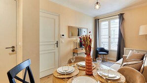 A dining area with a table set for four, a vase with flowers, and a view of the city through large windows. - Lovely apartement  with AC - Center of Paris (Paris)