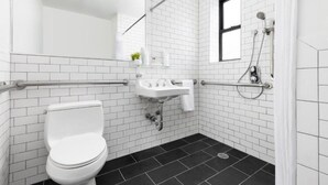Un bany modern amb rajoles blanques tipo metro, un vàter blanc, un lavabo amb mirall i una zona de dutxa.