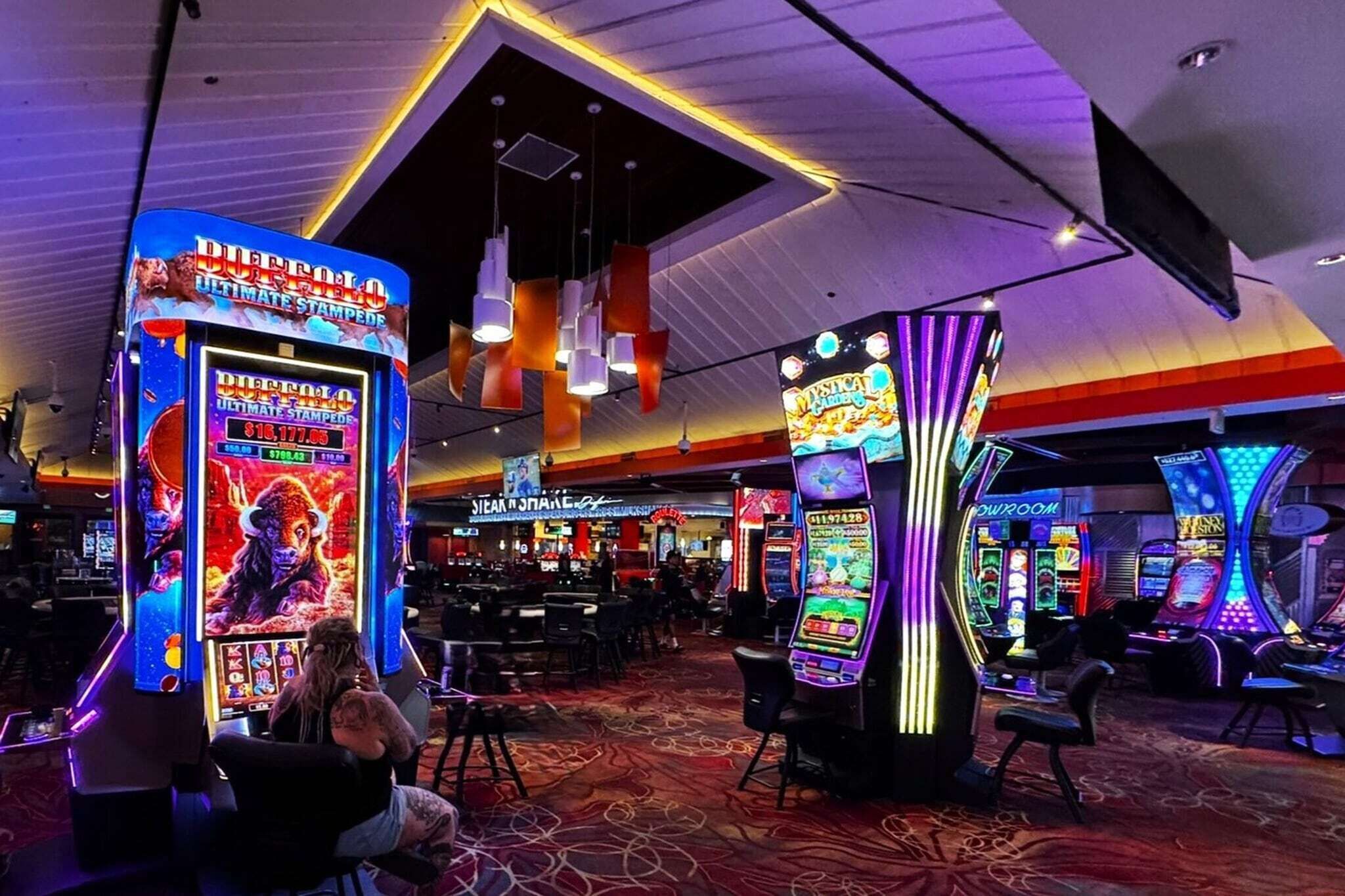 A casino with slot machines, a bar area, and a large illuminated sign.