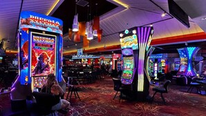 Un casino avec des machines à sous, un bar et une grande enseigne lumineuse.