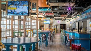 Un espace bar avec des tables et des tabourets, un écran de télévision et un comptoir.