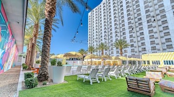 A hotel with a pool area, palm trees, and a large building in the background.