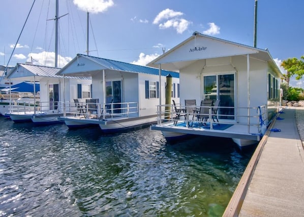 Floating houses with outdoor seating, a dock, and a clear sky.