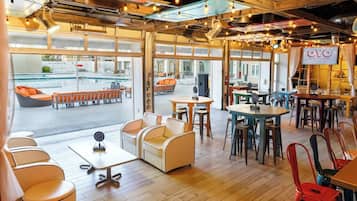 A hotel lobby with a pool view, wooden floors, and modern furniture.