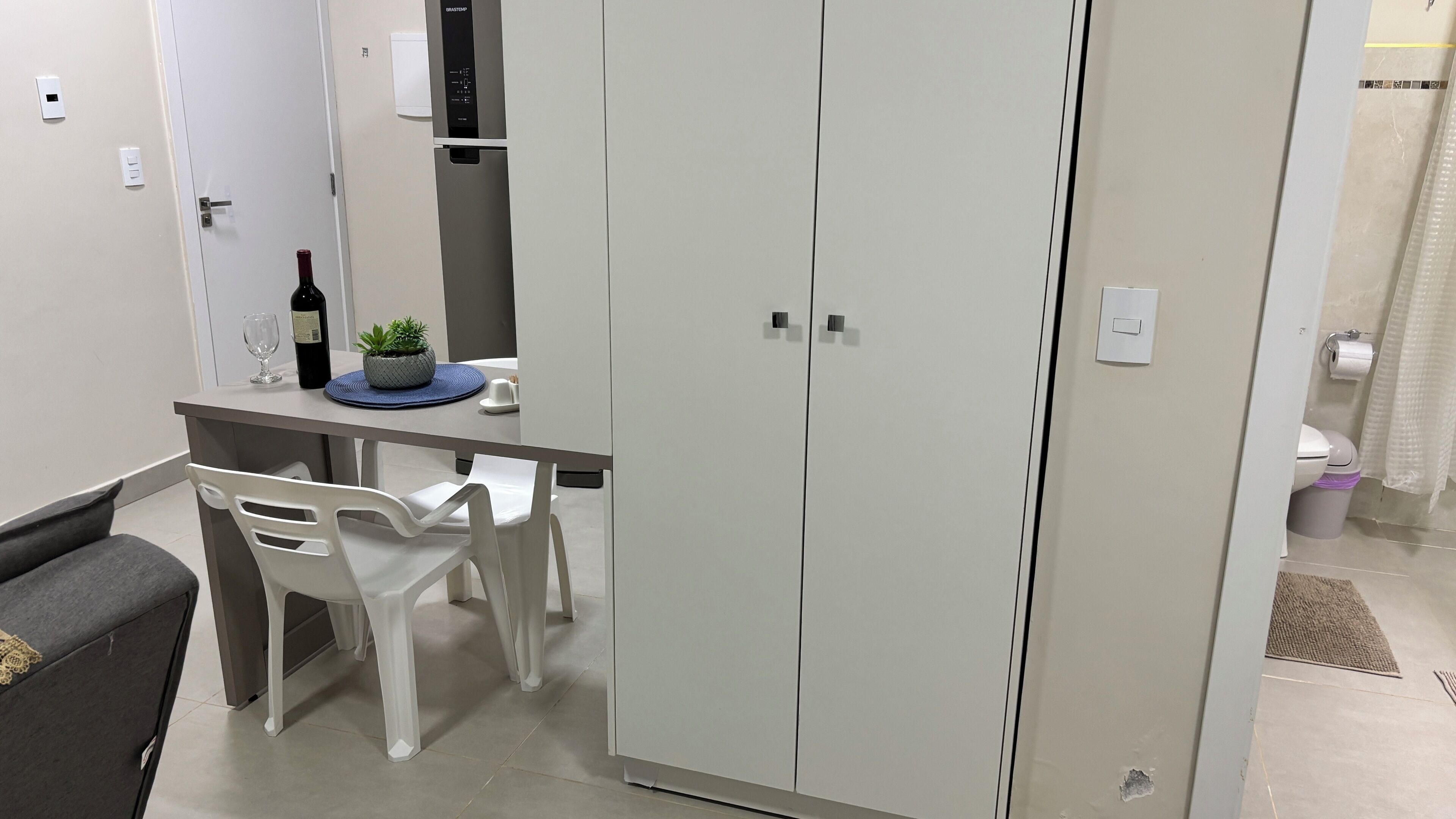 Un espacio habitable compacto con kitchenette, una zona de comedor con mesa y sillas, y un armario.