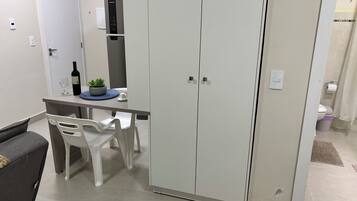 Un espacio habitable compacto con kitchenette, una zona de comedor con mesa y sillas, y un armario.
