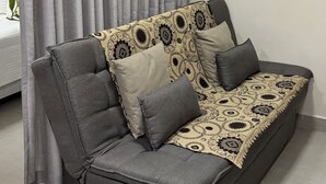 A grey sofa with patterned cushions, a grey curtain, and a white wall. - Ravello Residential AP03 Foz do Iguaçu (Foz do Iguaçu)