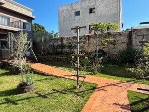 Ein Innenhof mit Pflasterweg, einem kleinen Baum und einem Gebäude mit Mauerwerk.