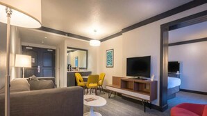 Une chambre d’hôtel avec un canapé, une petite table ronde, un téléviseur, une chaise rouge et un lit.