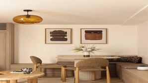 A modern living room with a round wooden coffee table, two woven chairs, a sofa with patterned cushions, a small side table, and a hanging pendant light. - Modern Apartment a/c 1BR/2P - Saint-Germain (Paris)