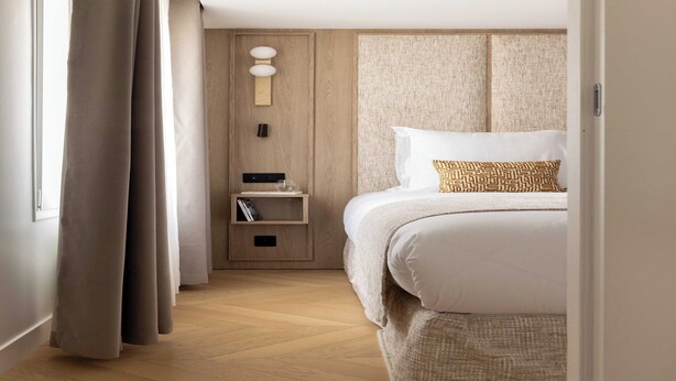 A hotel room with a bed, a bedside table, a nightstand, and a wall-mounted light fixture. - Modern Apartment a/c 1BR/2P - Saint-Germain (Paris)