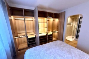 Ein Schlafzimmer mit Bett, begehbarem Kleiderschrank und Duschbereich.