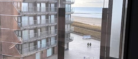 A multi-story building with balconies overlooking a beach.