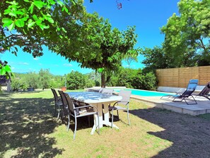 A backyard with a pool, a table with chairs, and a wooden fence.