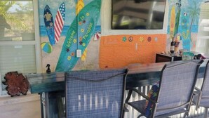 Área de bar com um mural, duas cadeiras e um balcão.