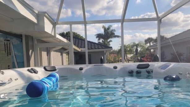 Uma piscina com superfície de água azul cristalina, um flutuador azul e uma estrutura branca à beira da piscina.
