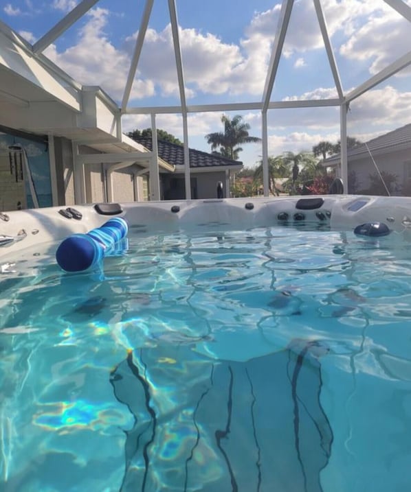Una piscina con superficie de agua azul cristalina, un flotador azul y una estructura blanca junto a la piscina.