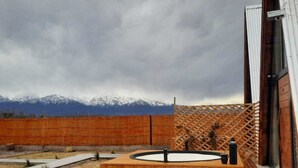 Un espace extérieur aménagé en bois, avec des sièges, un jacuzzi et une terrasse en bois, offrant une vue sur les montagnes.