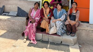 A group of people seated outside a hotel named 'Hotel Shri Ji Palace' with a sign indicating rooms are available. - Hotel Shri Ji Palace (Rajnagar)