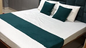A bed with a wooden frame, a dark headboard, and a teal bedspread. - Hotel Shri Ji Palace (Rajnagar)