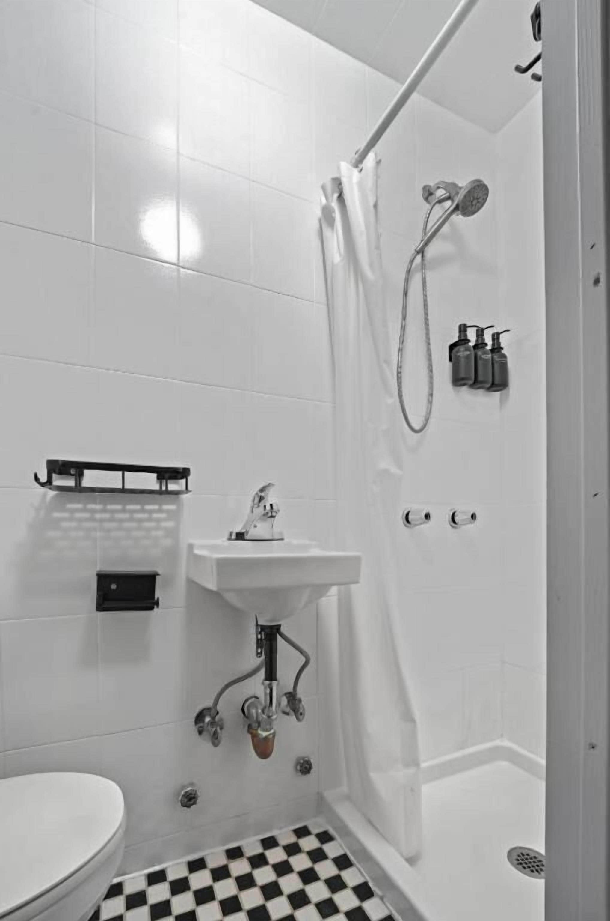 Un bagno con WC, lavandino, doccia e pavimento piastrellato a scacchi.