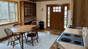 Eine Küche mit Holzausstattung, einem Esstisch mit Stühlen, einem Deckenventilator und einem Herd.
