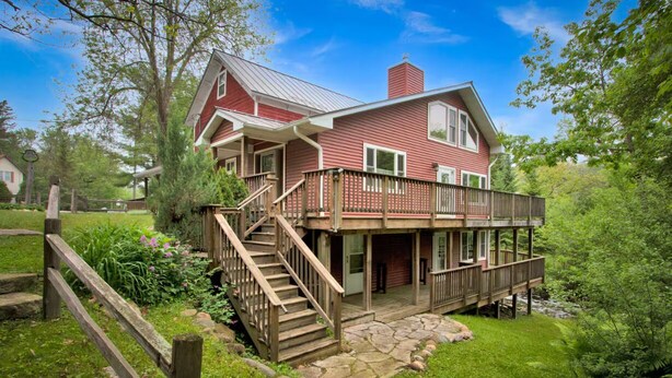 Ein zweigeschossiges Haus mit Veranda, einer Treppe und einem Steinweg.