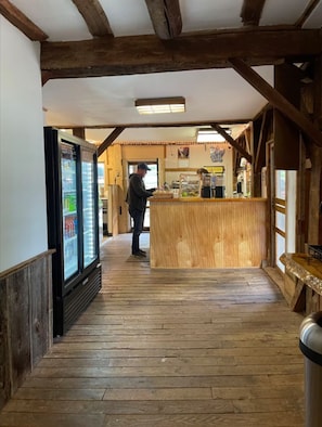A wooden interior with a counter, a refrigerator, and a person standing at the counter. - 2-bedroom mill in adorable Wautoma with AC and charm (Wautoma)