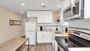 A modern kitchen with white cabinets, a built-in microwave, a stove, and a refrigerator. - Cozy 1-bedroom apartment in enjoyable Houston with AC (Houston)