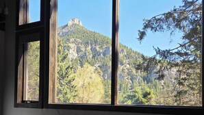 A room with a table and chairs, a window with a view of a mountainous landscape. - Mountain Home in Gallatin Canyon with Home Theater and 3 Spacious BR/BA (Gallatin Gateway)
