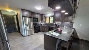 A modern kitchen with stainless steel appliances, dark wood cabinets, and a granite countertop. - Mountain Home in Gallatin Canyon with Home Theater and 3 Spacious BR/BA (Gallatin Gateway)