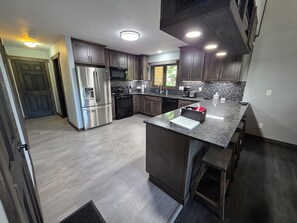 A modern kitchen with stainless steel appliances, dark wood cabinets, and a granite countertop. - Mountain Home in Gallatin Canyon with Home Theater and 3 Spacious BR/BA (Gallatin Gateway)