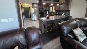 A modern kitchen with dark wood cabinets, stainless steel appliances, and a bar area with stools. - Mountain Home in Gallatin Canyon with Home Theater and 3 Spacious BR/BA (Gallatin Gateway)