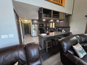 A modern kitchen with dark wood cabinets, stainless steel appliances, and a bar area with stools. - Mountain Home in Gallatin Canyon with Home Theater and 3 Spacious BR/BA (Gallatin Gateway)