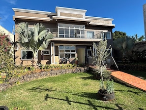 A two-story house with a balcony, a stone wall, and a grassy lawn. - Ravello Residential AP04 Foz do Iguaçu (Foz do Iguaçu)