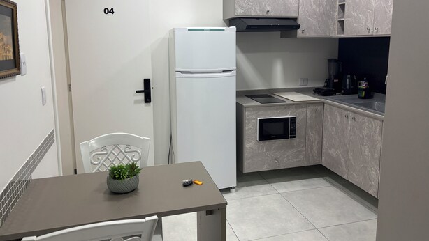 A compact kitchen with a refrigerator, microwave, and a small countertop. - Ravello Residential AP04 Foz do Iguaçu (Foz do Iguaçu)