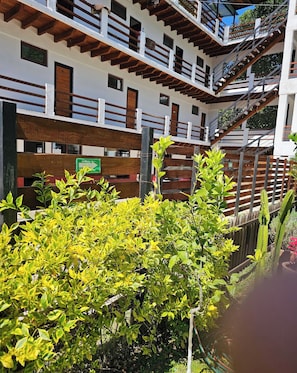 Un immeuble à plusieurs étages doté de balcons, d’une clôture en bois et d’un panneau indiquant une direction.