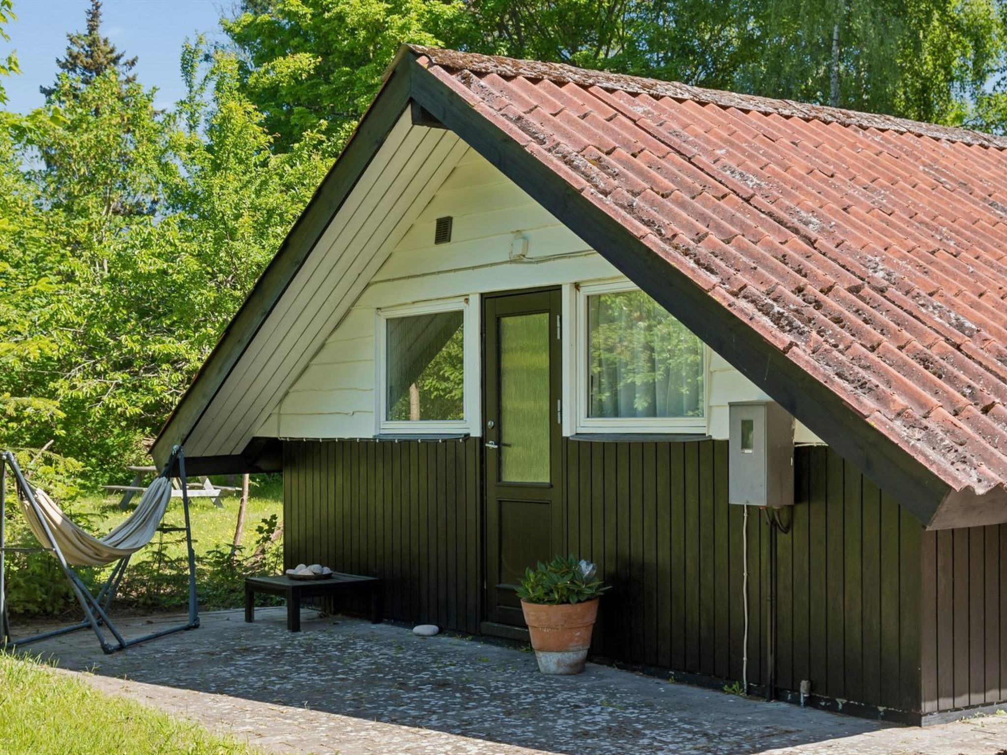 A small, single-story building with a sloped roof, a front door, and a window.