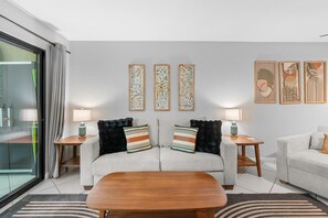 Ein modernes Wohnzimmer mit einer Couch, zwei Beistelltischen, einem Couchtisch und drei Wandbildern.