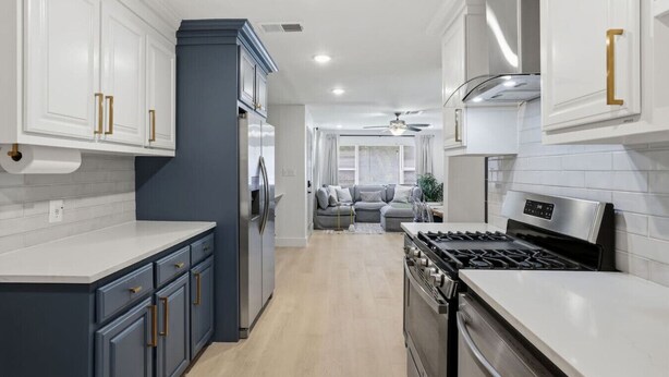 Una cucina moderna con mobili bianchi, un frigorifero blu e un fornello a gas.