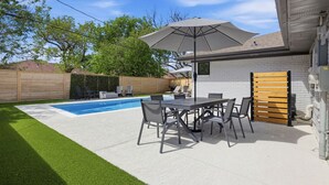 Un cortile con piscina, mobili da patio e una recinzione in legno.
