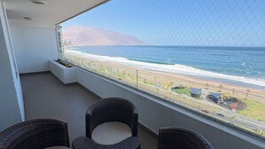 Een balkon met rieten meubels en uitzicht op de oceaan.