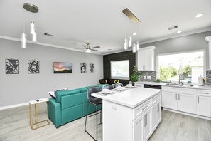 Een moderne keuken met witte kasten, een blauwgroene bank en hanglampen.