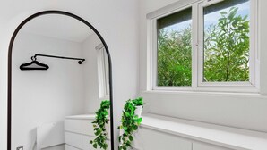 A room with a white dresser, a radiator, a black hanger, and a window with a view of green foliage. - 2BR • New Listing Discount • Free Parking (West Sussex)