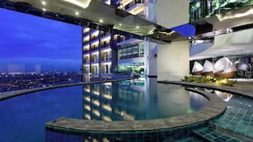 A modern indoor swimming pool with a city view, a covered outdoor area, and a restaurant.