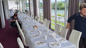 A long dining table with white tablecloths and chairs, set against a backdrop of a scenic outdoor view. - Rooms Denadija Double 1 (Hrvatska Kostajnica)