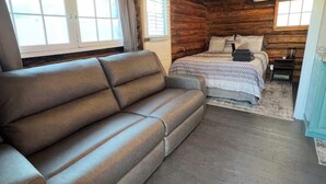 A log cabin interior with a sofa, a bed, wooden floors, and a window. - Cozy Rustic Cabin in the City (Richfield)