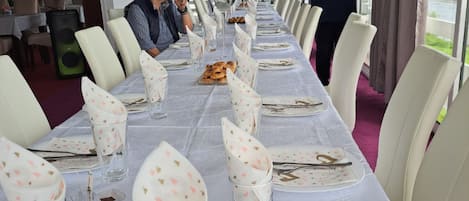 Ein langer Esstisch mit weißen Tischdecken und blumigen Servietten, gedeckt für eine Mahlzeit.