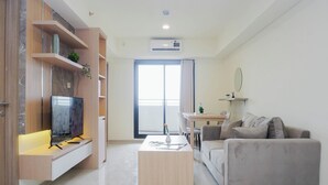 A modern living room with a flat-screen TV, a sofa, a coffee table, and built-in shelves. - Neat 3Br For 4 Pax At Meikarta District 2 Apartment (Cikarang)